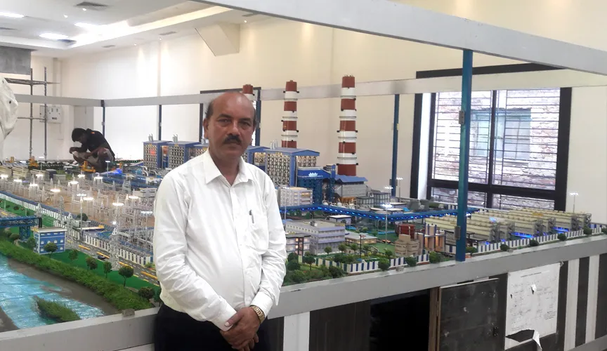 A Tech Mech Services team member beside a large scale model of a thermal power plant in the workshop