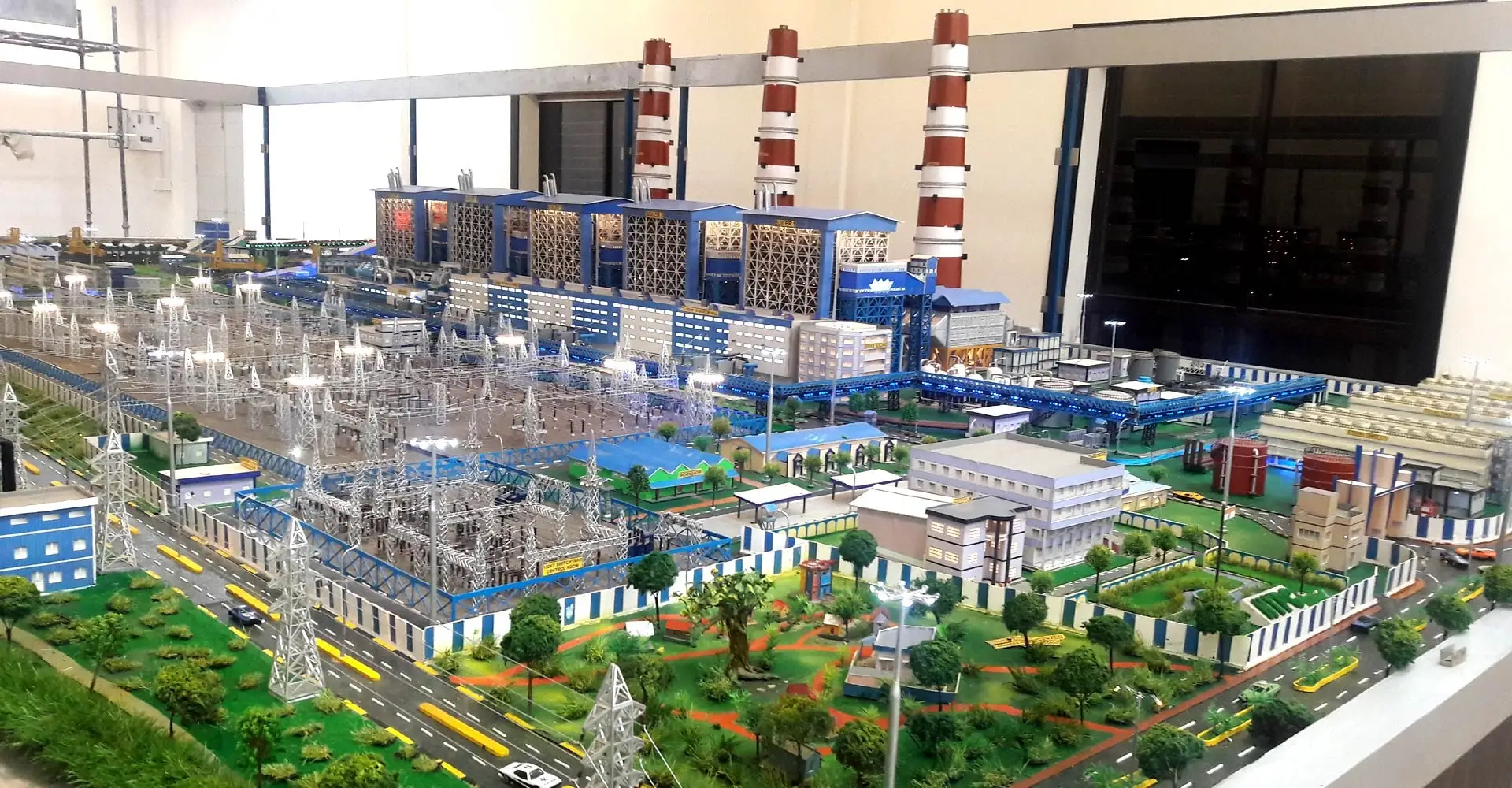 A detailed scale model of a thermal power plant with chimneys, switchyard and buildings